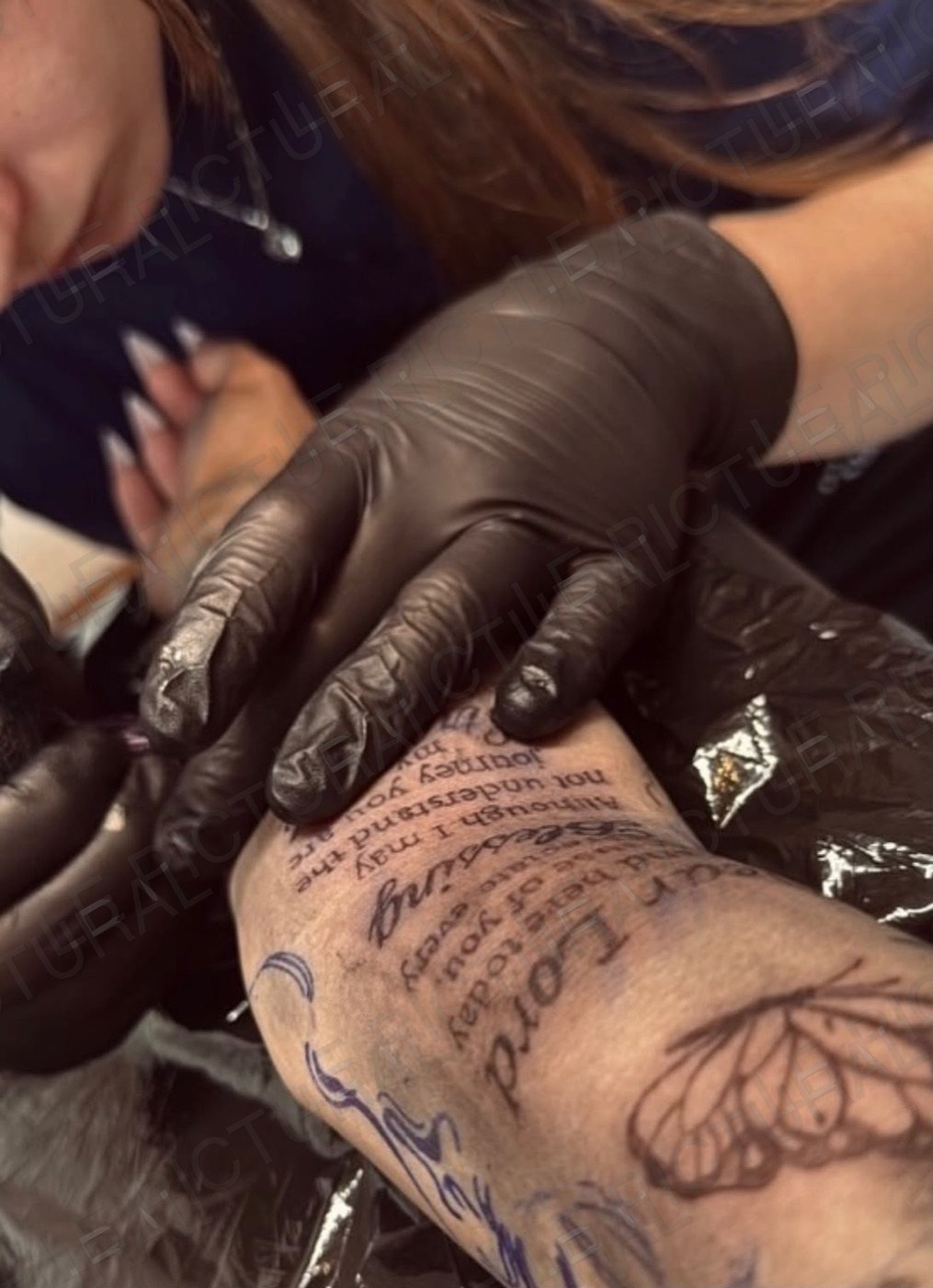 Tatouage en cours de réalisation : texte et papillon sur un avant-bras